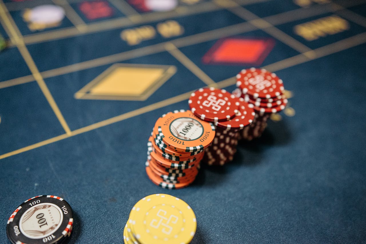Stack of red, orange, and yellow poker chips on a roulette table.